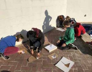 children making cardboard sundials outdoors